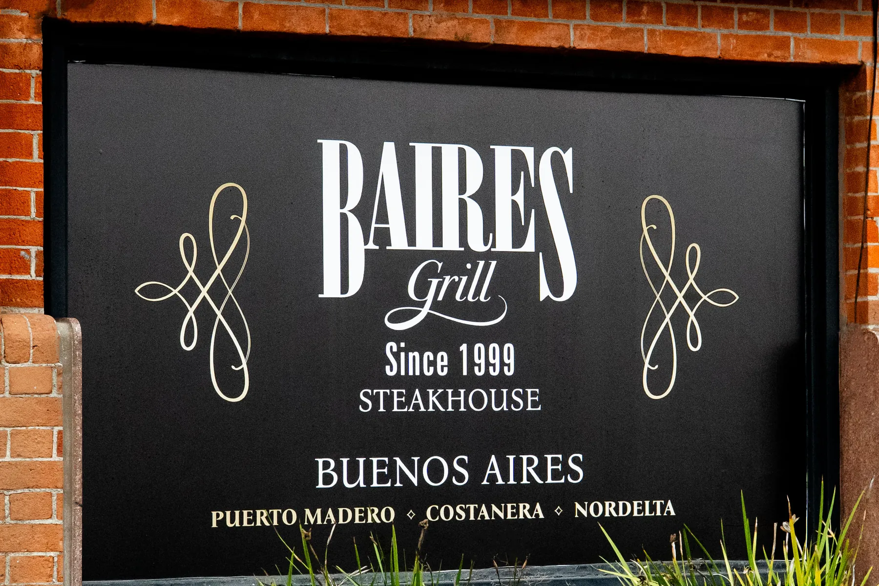 El cartel de Baires Grill sobre el frente de ladrillo del local de Puerto Madero
